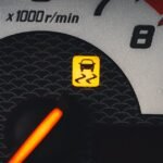 Close-up of a car dashboard showing a yellow traction control warning light.