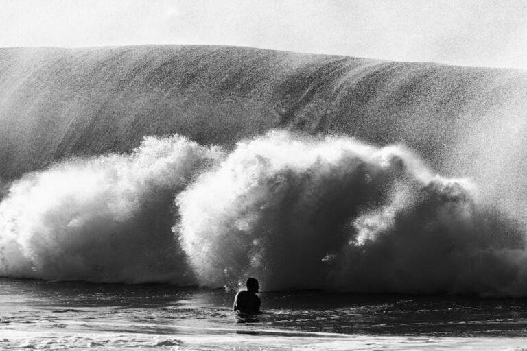 Silhouette of a person facing a large ocean wave in Hawaii, capturing the raw power of nature.