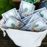 A top view of a sack brimming with US 100 dollar bills, symbolizing wealth and prosperity.